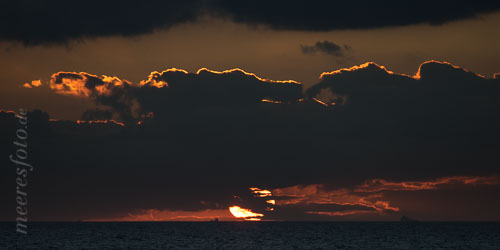  Schiffe am Horizont vor Ahrenshoop mit der großen glühenden Scheibe der untergehenden Sonne unter einer Wolkenbank