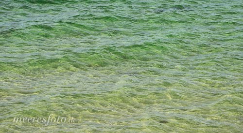 Die spiegelnde Wasseroberfläche der Ostsee über einer Sandbank  zwischen Brodten und Travemünde an einem sonnigen Tag