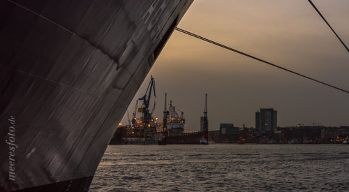 Der Bug eines Schiffes und die Elbe des Hamburger Hafens im letzten Licht der untergegangenen Herbstsonne