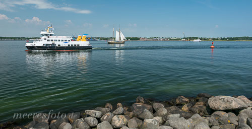 Eine Fähre und ein Tradionssegler auf der Ostsee der Kieler Förde vor dem Ehrenmal der U-Bootfahrer in Heikendorf