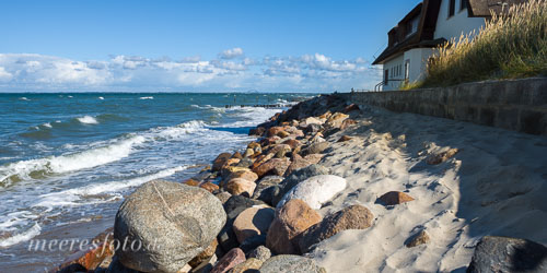 Schwere Steine als Küstenschutzmaßnahme am Strand von Graswarder in sommerlicher Brandung