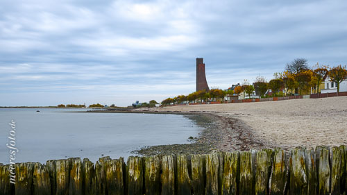 Eine Holzbuhne am Strand von Laboe und das Marine-Ehrenmal an einem trüben Herbsttag