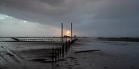  Schwere Regenwolken liegen bei Sonnenuntergang über dem Strand von  Sankt Peter-Ording