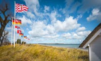 Flaggen und Dünengras im frischen Wind eines sonnigen Tages an der Ostsee in Scharbeutz