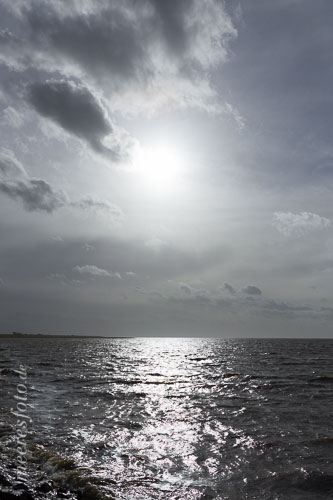 Die Sonne spiegelt sich im Gegenlicht auf der Nordsee im Mündungsbereich der Eider