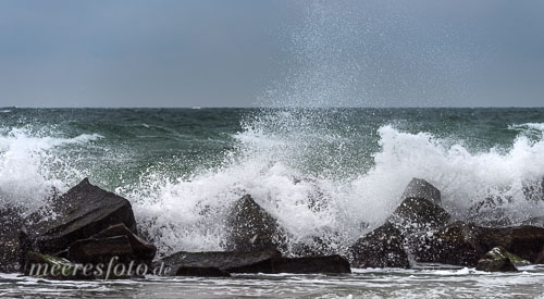  Wellen brechen sich mit großer Gischt an den Wellenbrechern vor Wustrow