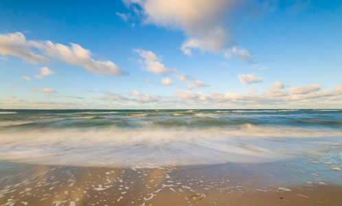 Auflaufende Wellen am Schwedeneck – Das Bild zeigt den Strand von Surendorf an einem sonnigen Tag mit kräftigen, auflandigem Wind.