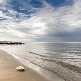 TITEL: »Stein am Strand von Hohwacht« DETAIL: Ein einzelner Stein liegt an diesem ruhigen Sommertag am Ufer. Der Blick geht über die Hohwachter Bucht Richtung Behrensdorf. ORT: Ostsee, Hohwachter Bucht, Hohwacht, Strand.