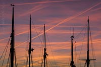  TITEL: »Masten von Traditionsseglern und Kondensstrefen am Himmel bei Sonnenuntergang – 001« ORT: Ostsee, Kieler Bucht, Kiel, Hörn.