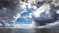  »Wattenmeer mit Wolken und Sonne bei Flut« DETAIL: Der Blick über diesen Bereich der Nordsee bei Schlüttsiel zeigt am Horizont Teile der Haligen Habel, Krudtswarft und Oland.
