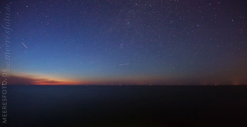  Blick auf den Horizont vor dem Schönberger Strand in einer sternenklaren Sommernacht –  DETAIL: Helle Streifen am Nachthimmel sind die Lichtspuren von Flugzeugen.