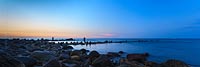  Meerforellenangler im Licht des späten Abends vor Strande –  DETAIL: Nach Sonnenuntergang wagen sich neben den Meerforellen auch Dorsche dicht unter Land. Zwei Angler stehen zwischen den Steinbuhnen im Wasser.