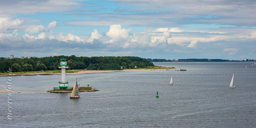 Der Falkensteiner Strand, der Leuchtturm Friedrichsort und Segler auf der Kieler Förde an einem Sommertag mit eindrucksvollen Wolken am Horizont