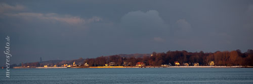 Das warme Liicht des Sonnenuntergangs fällt auf das Ostsufer der Kieler Förde an einem kalten Winterabend