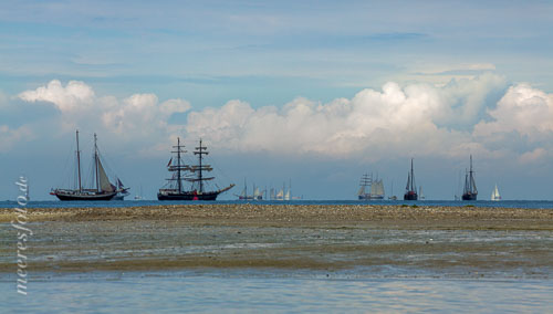  Historische Segelschiffe und Segelboote am Horizont der Kieler Bucht hinter eine Sandbank vor dem Strand von Laboe