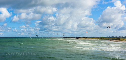 Der Strand von Heiligenhafen und Kitesurfer an einem sonnigen Tag mit kräftigem Westwind