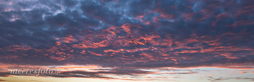  Wolken werden durch Streiflicht eines Sonnenuntergangs partiell von unten mit glutrotem Licht beleuchtet