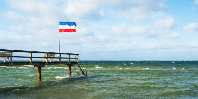 Badesteg mit Flagge im Sturm in Niendorf