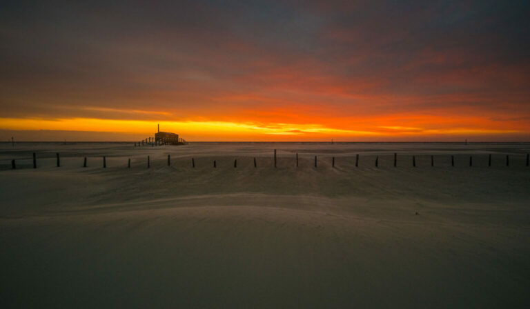 Strandschuppen im Abendrot mit Zaun